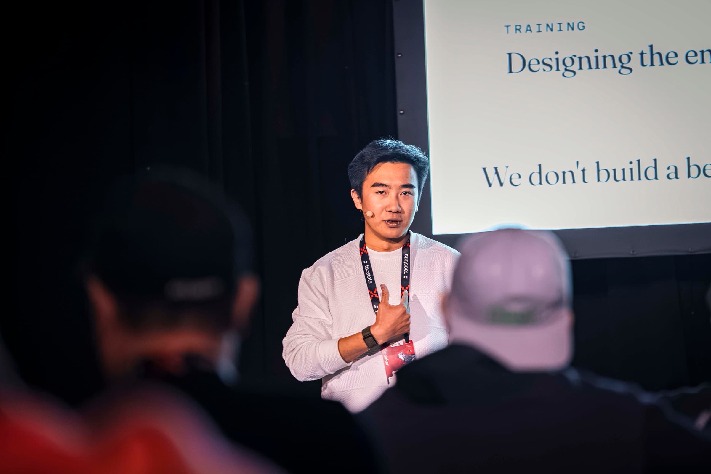 Xavier Lyu speaking to a seated audience, a slide reading Training: Designing the engine behind him